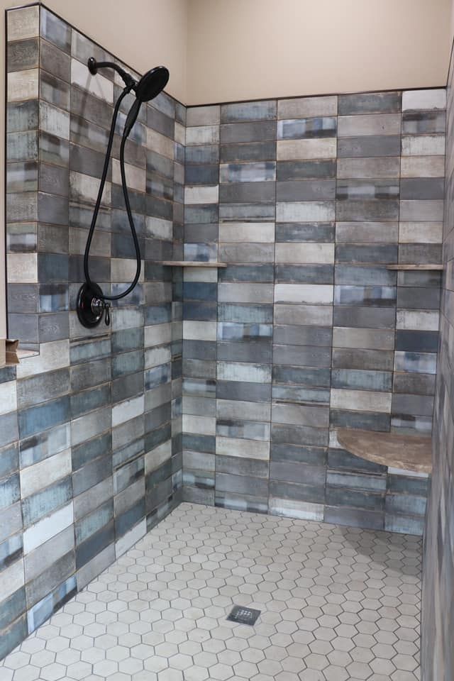A walk in shower with blue and white tiles and a shower head.