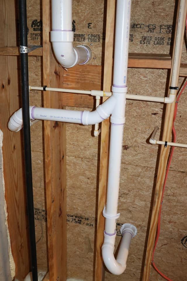 A bunch of white pipes are hanging from a wooden wall.