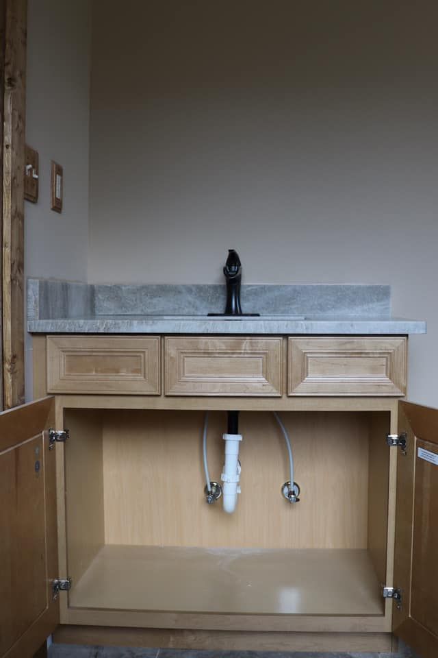 An empty bathroom vanity with the doors open and a sink underneath it.