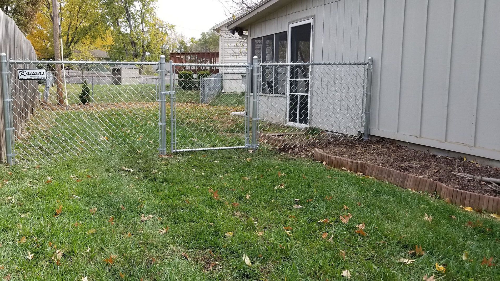 There is a chain link fence in the backyard of a house.
