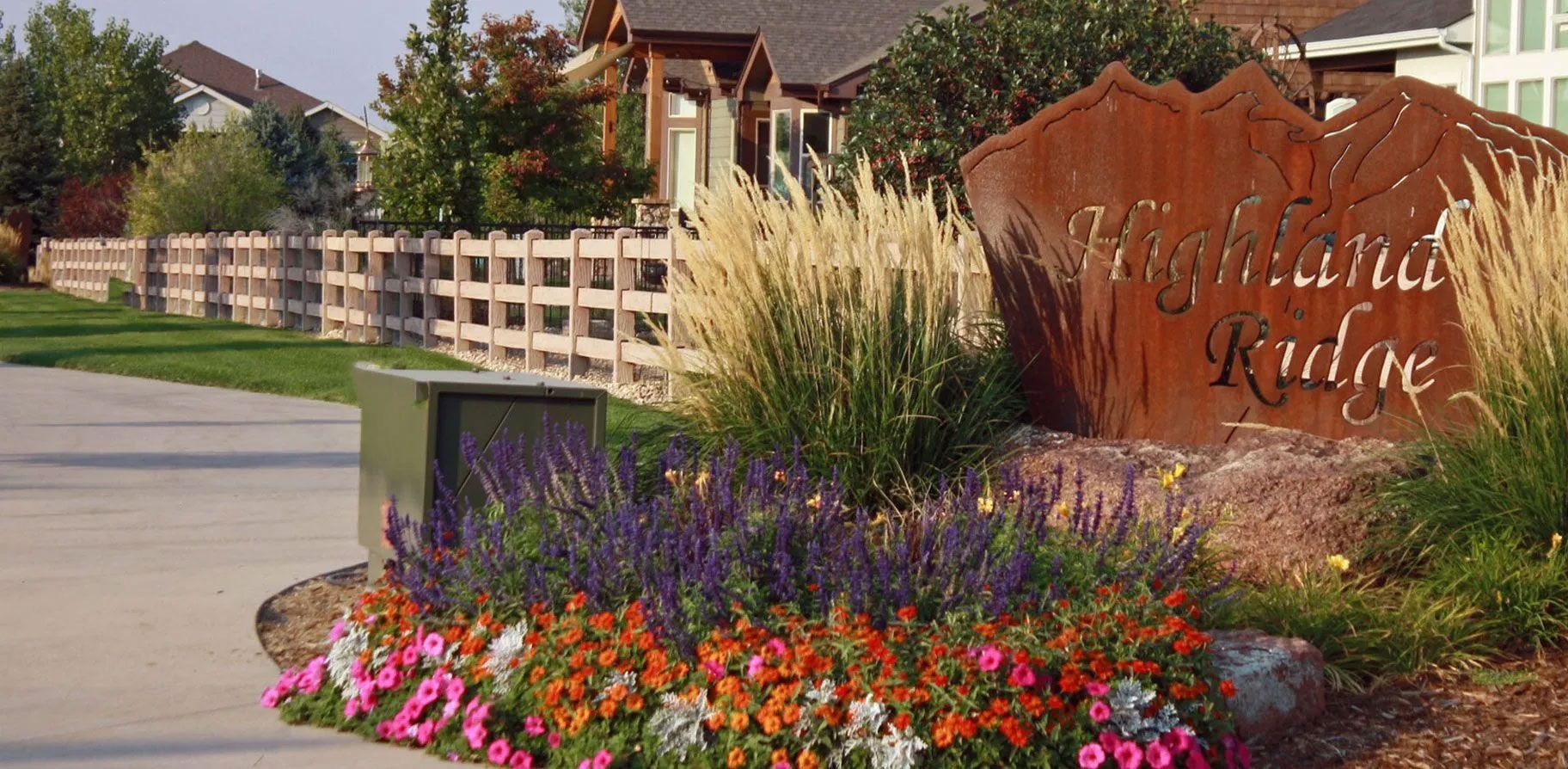 A sign for kingsford ridge is surrounded by flowers and grass
