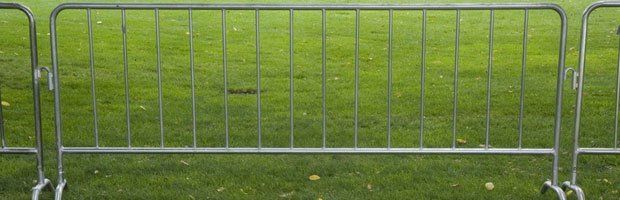 A metal fence is sitting on top of a lush green field.