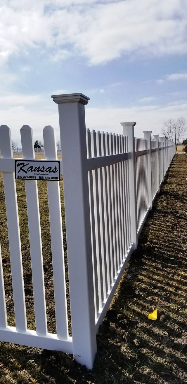 A white picket fence is sitting in the middle of a field.