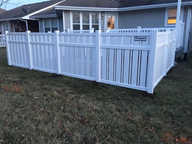 A white fence is sitting in front of a house.