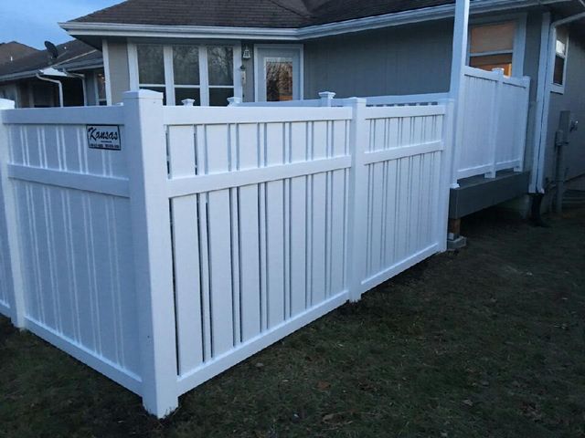 A white fence is in front of a house