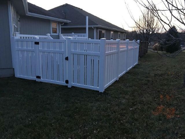 A white fence is in the backyard of a house.