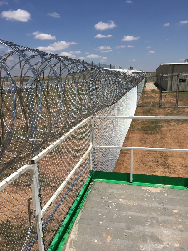 A barbed wire fence is surrounding a building in a field.