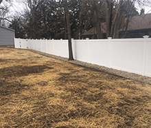 A white vinyl fence surrounds a lush green yard.
