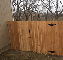A wooden fence with a gate in the backyard of a house.
