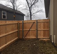 A wooden fence is in the backyard of a house.