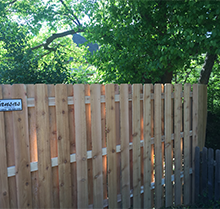 A wooden fence with a sign on it is surrounded by trees.