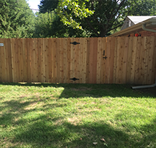A wooden fence is sitting in the middle of a lush green yard.