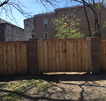A wooden fence with a gate in front of a building.
