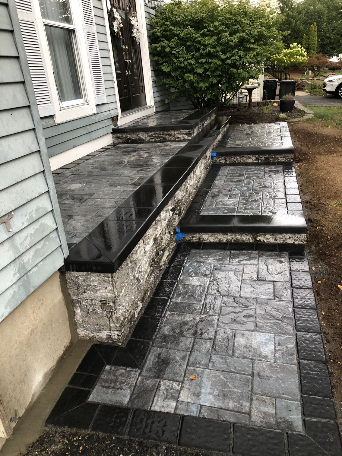 Stone steps and walkway leading to a light blue house with white shutters.