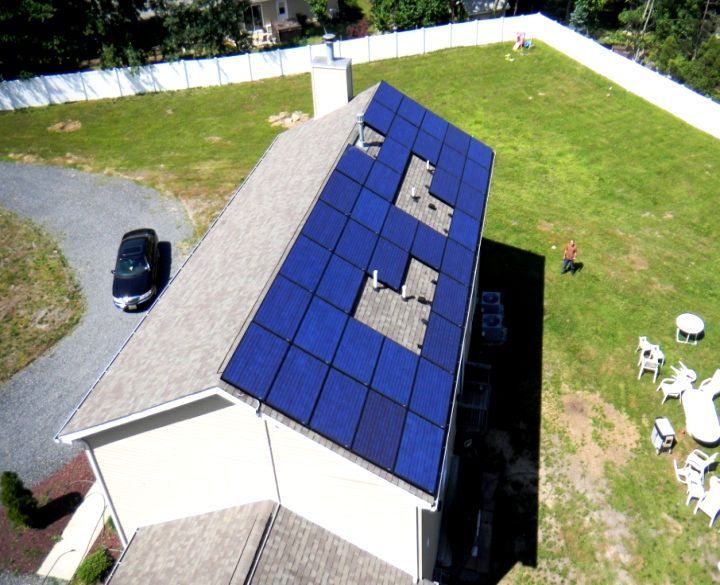 An aerial view of a house with solar panels on the roof.