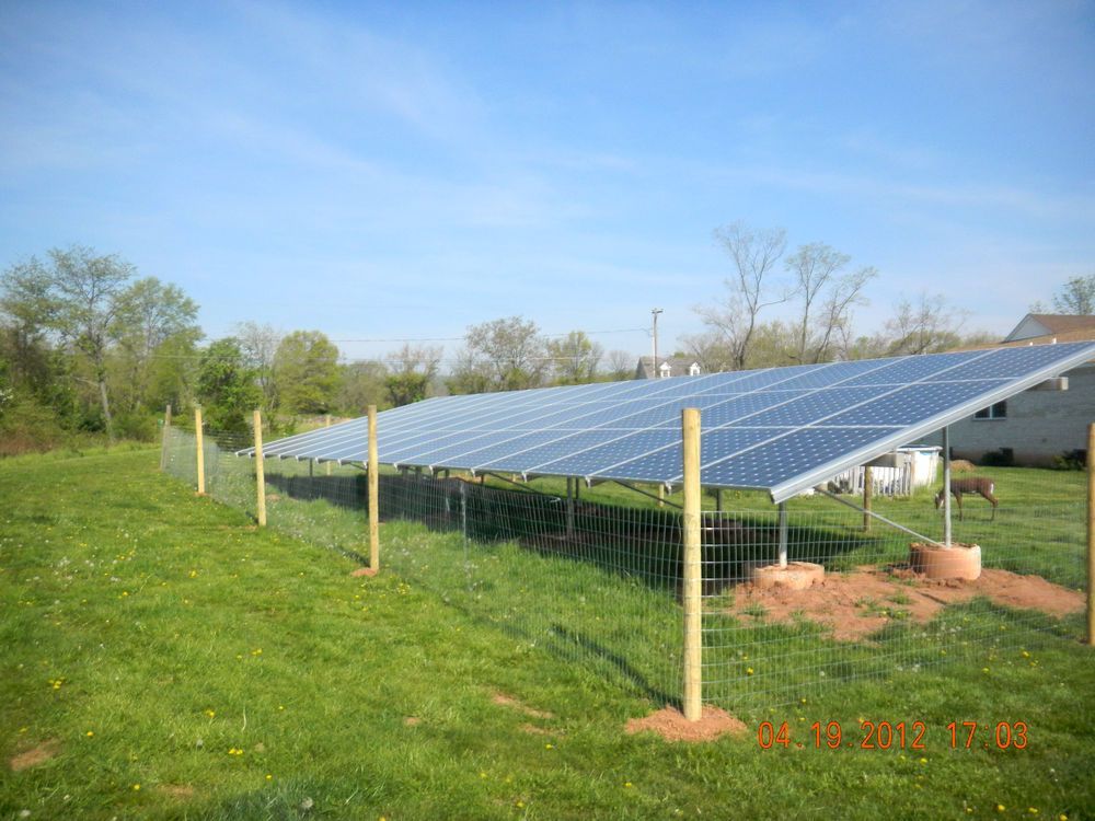 A row of solar panels sitting on top of a lush green field.