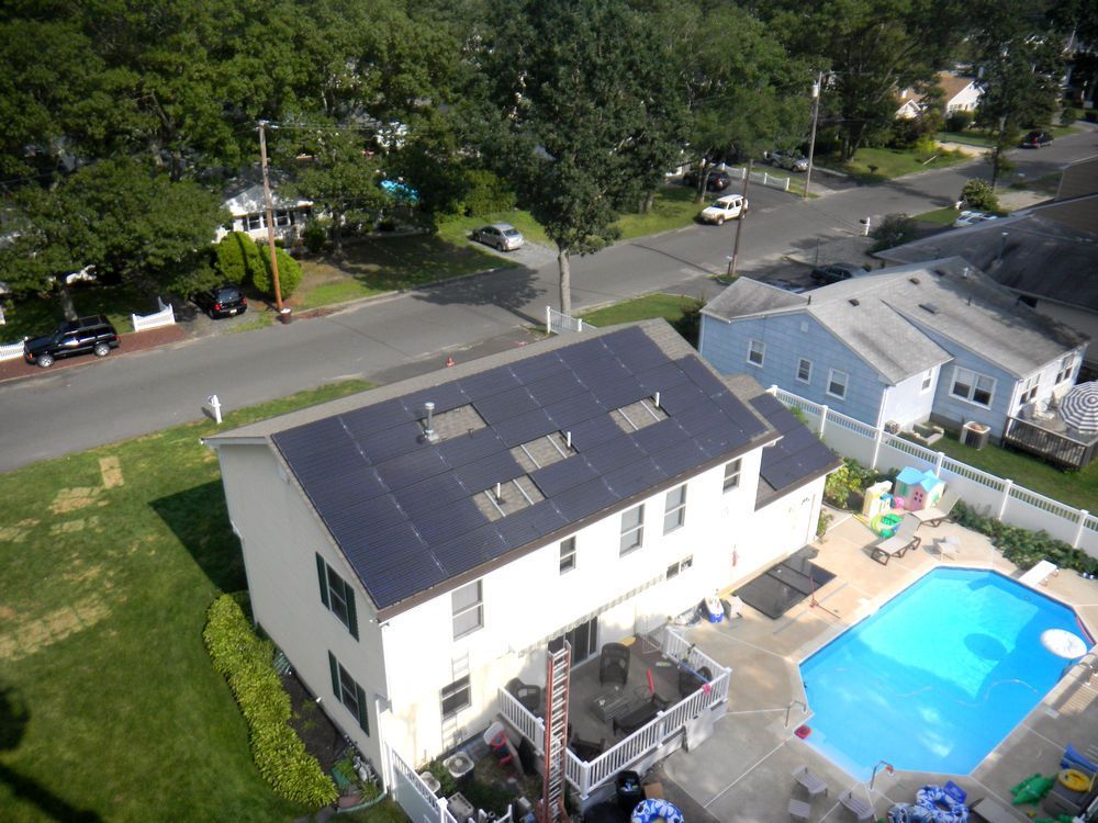 An aerial view of a house with a pool and solar panels on the roof.