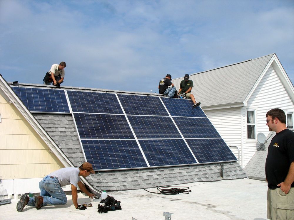 A group of men are installing solar panels on the roof of a house.