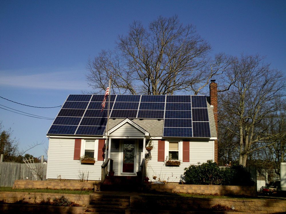 A white house with solar panels on the roof.