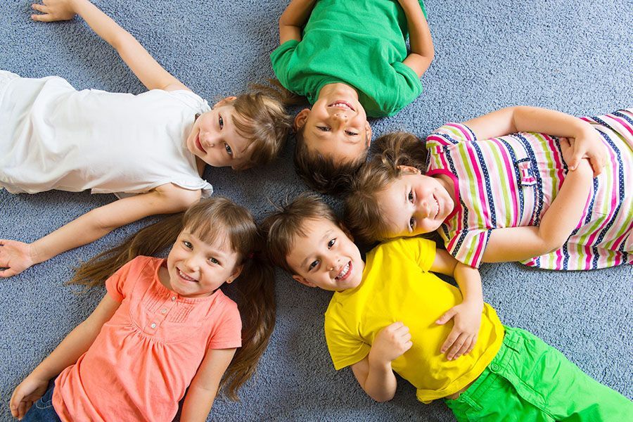 A group of children are laying on the floor in a circle.