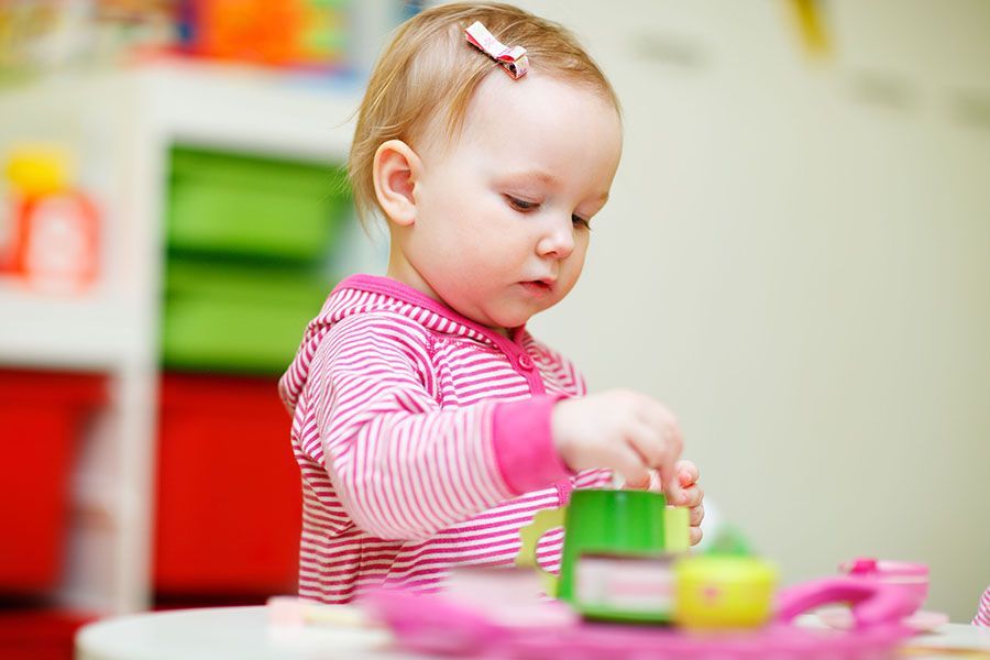 A little girl is sitting at a table playing with toys.