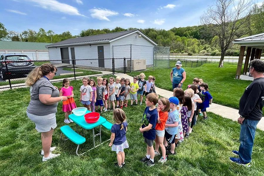 A group of children are standing around a picnic table.