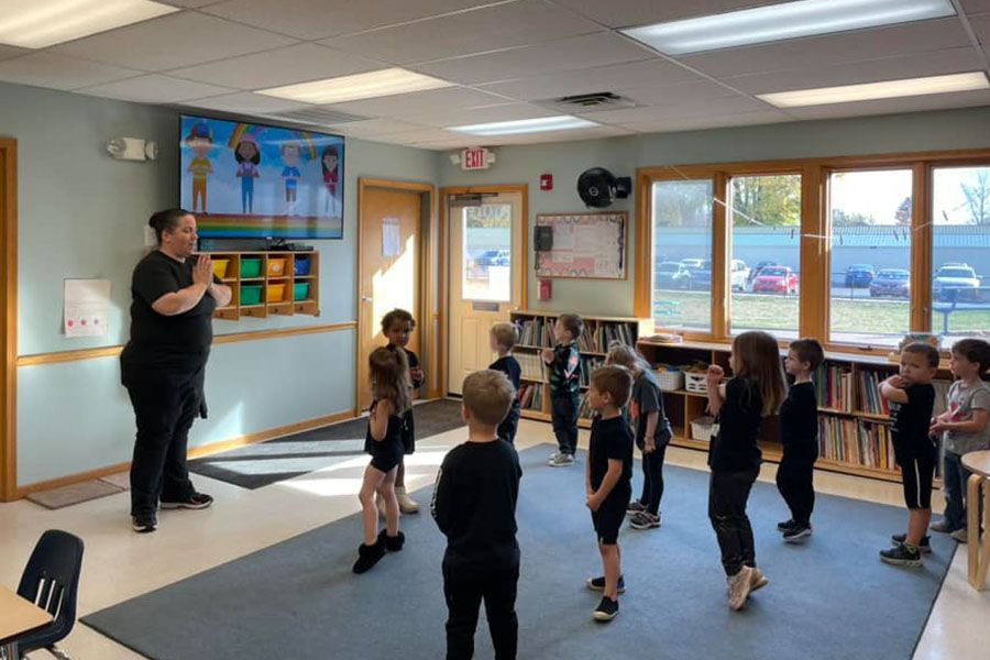 A group of children are standing in a circle in a classroom.