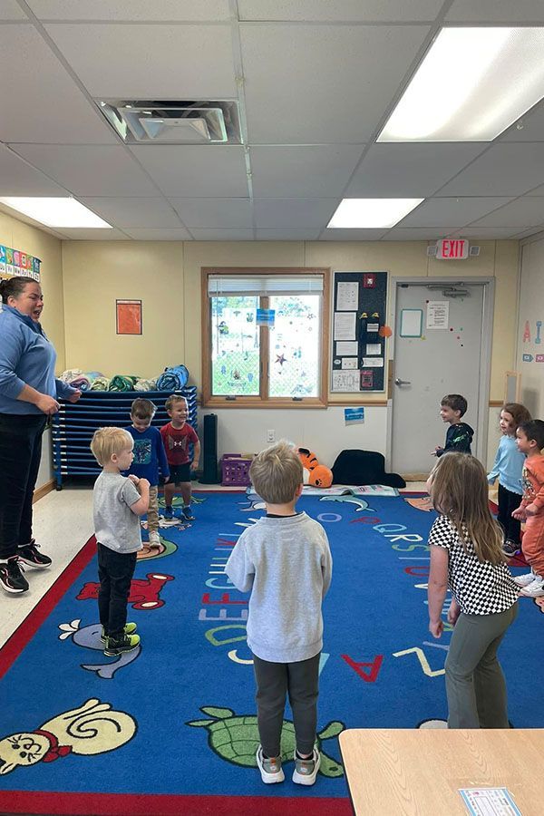 A group of children are standing in a circle in a classroom.