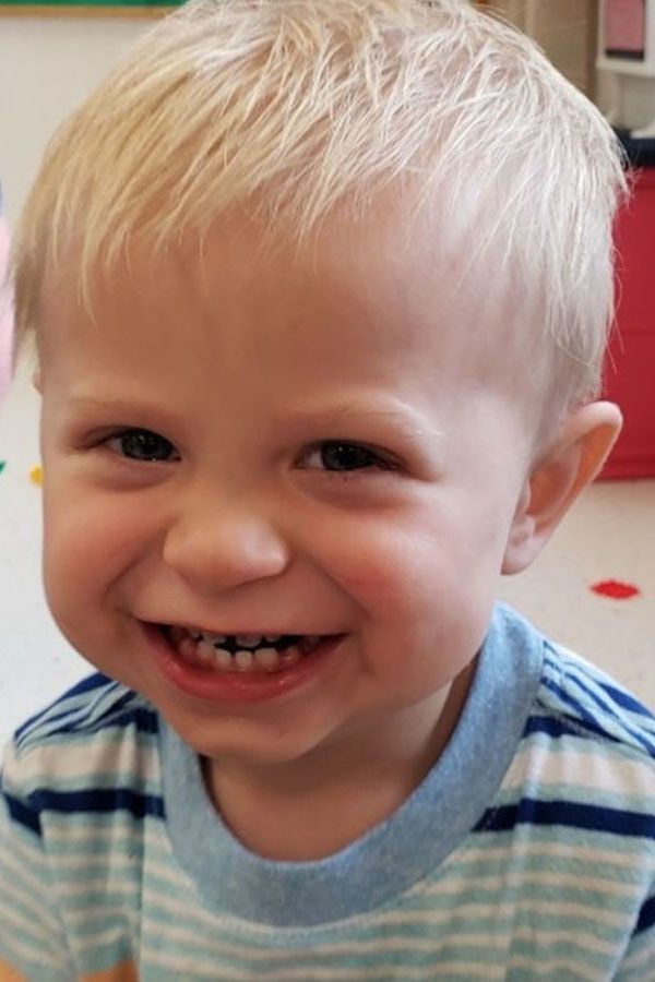 A young boy wearing a striped shirt is smiling for the camera.