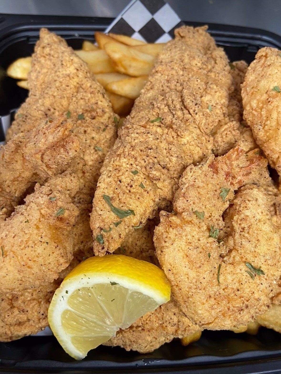 A tray of fried catfish and prawns with a lemon wedge