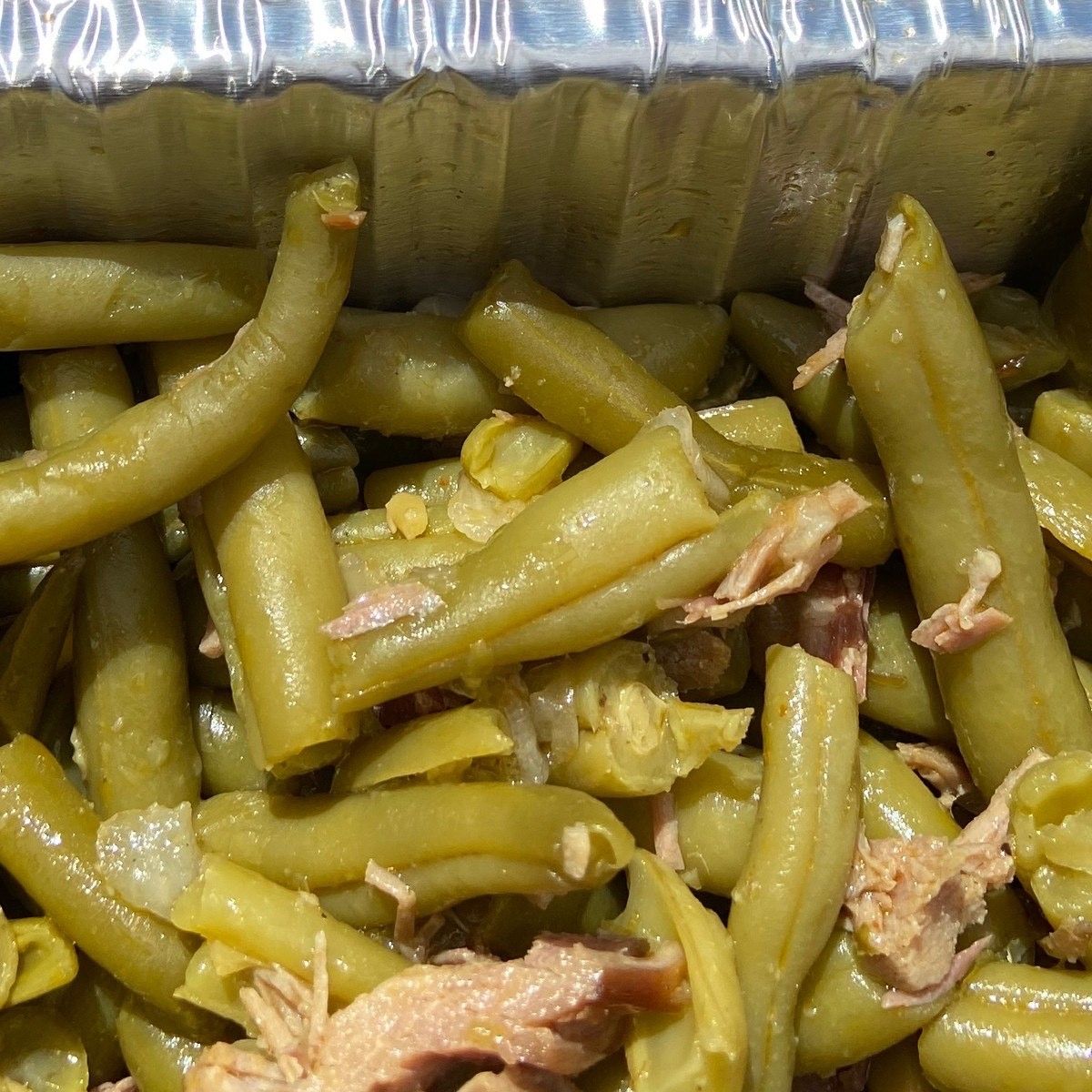 A close-up of green beans in a tin foil container