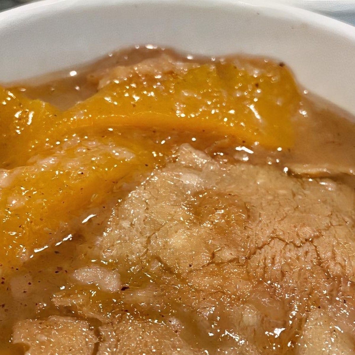 A close-up of a bowl of peach cobbler