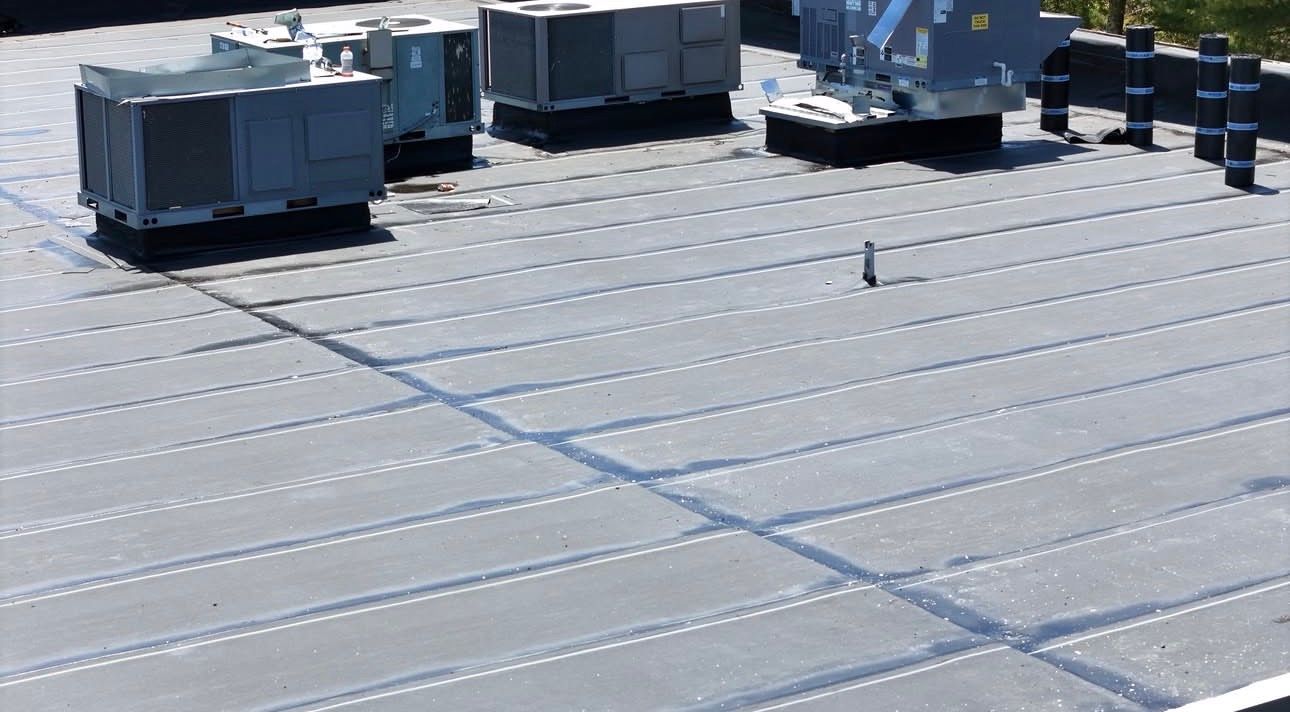 Rooftop with HVAC units and reflective metal panels under bright sunlight.