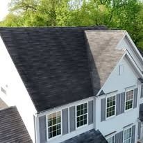 Aerial view of a house roof with dark shingles and a light gray gable section above white-framed windows