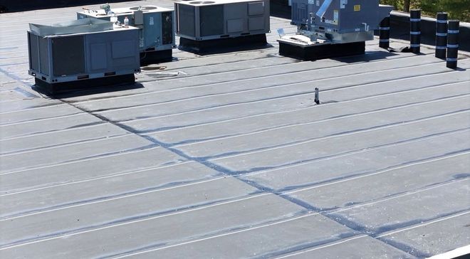 Rooftop HVAC units on a metal commercial roof under bright sunlight
