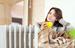 Woman in front of radiator with a cup of tea