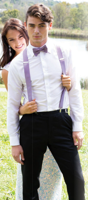 Man in white shirt, black pants, purple bow tie, and suspenders, with a woman hugging him outdoors.