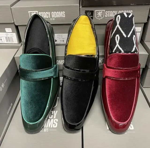 Three Stacy Adams velvet loafers in green, black, and red, displayed on boxes.