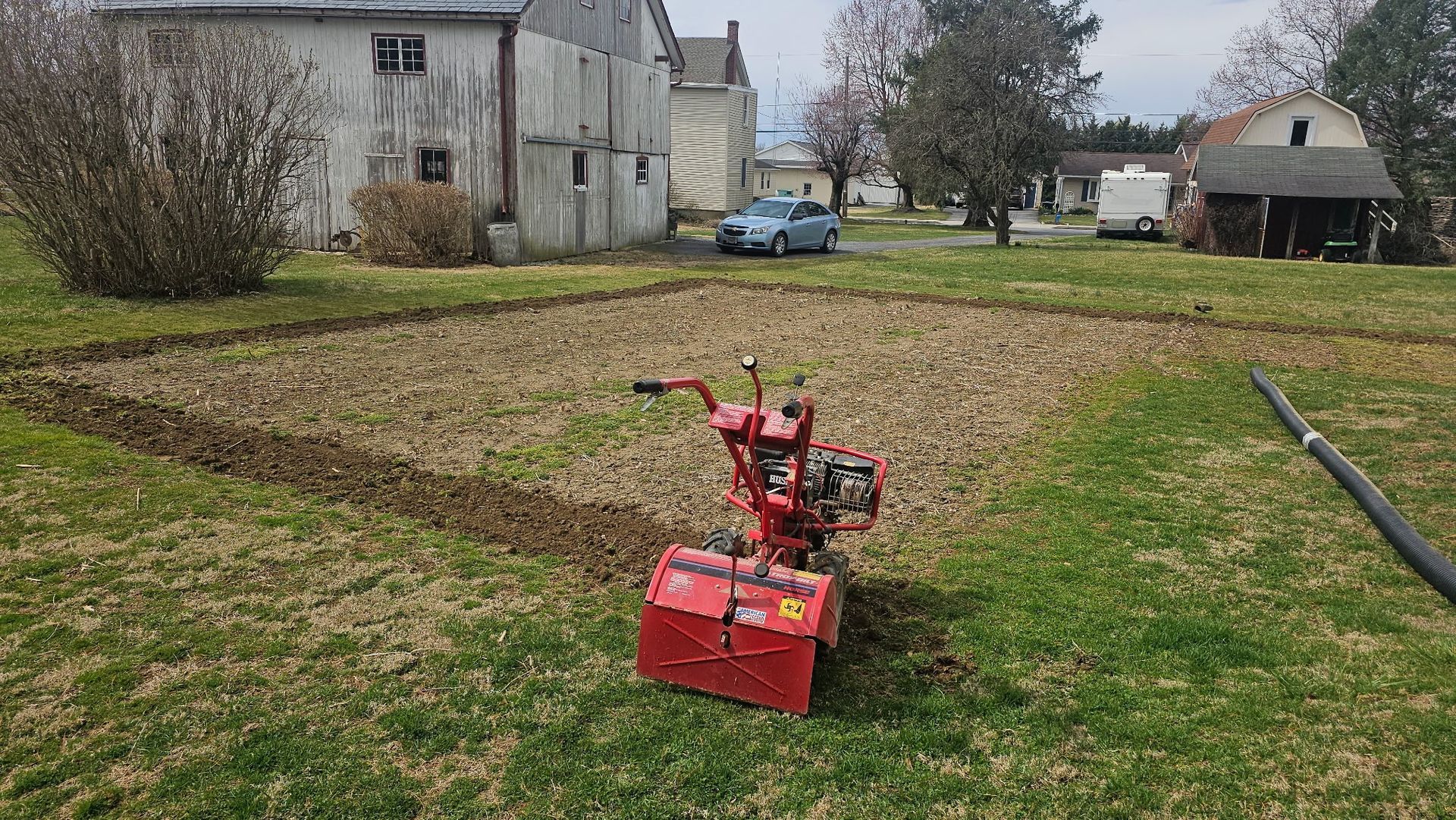 A red tractor is sitting in the middle of a grassy field.