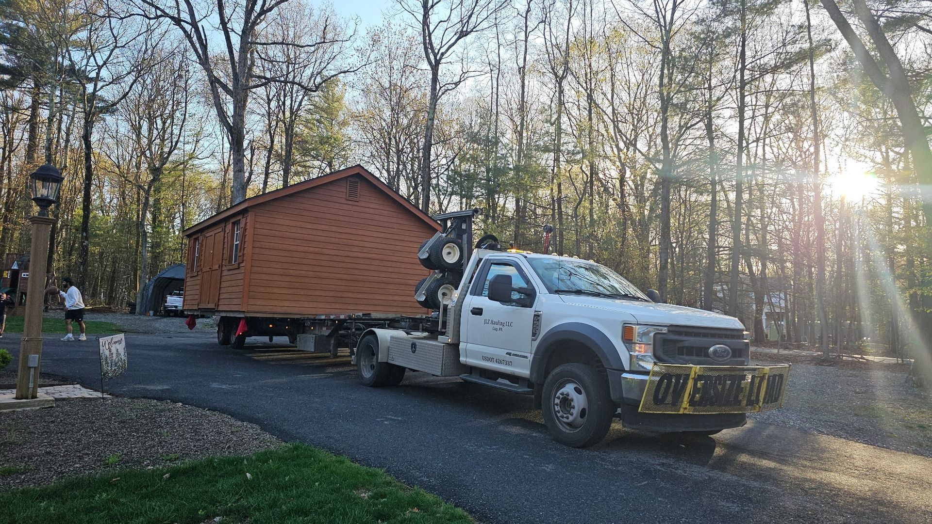 A tow truck is carrying a small house on a trailer.