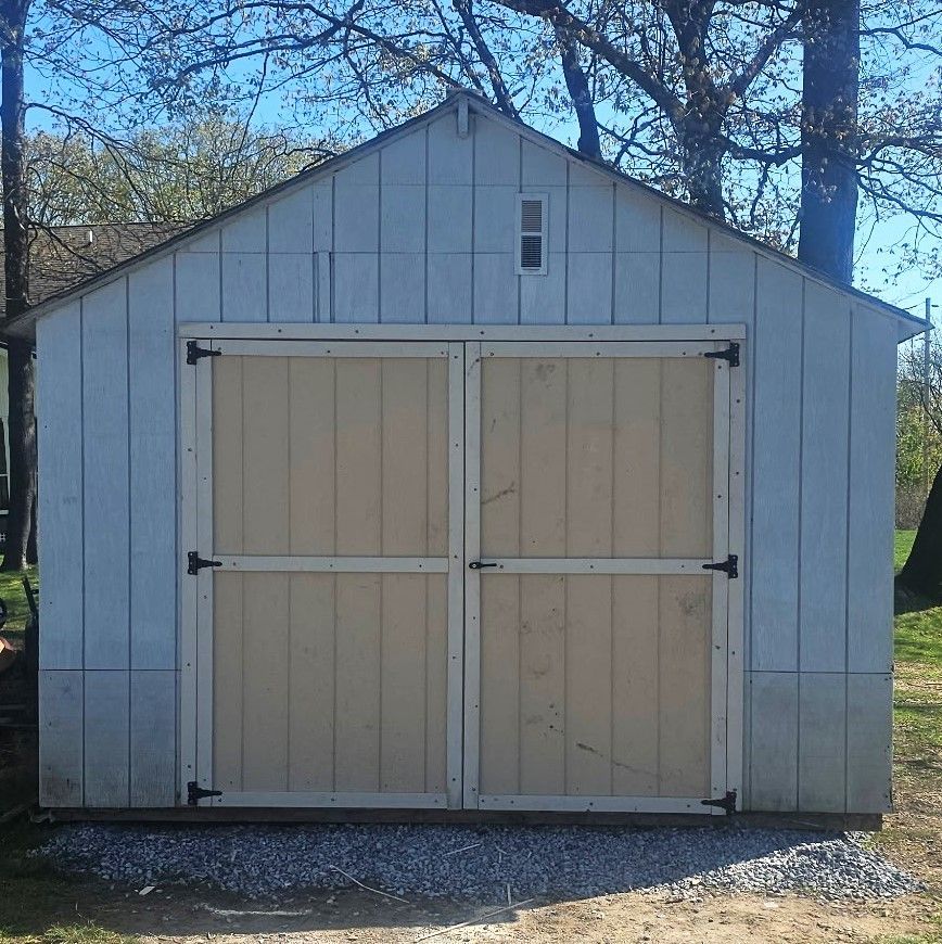 A white shed with wooden doors and a window