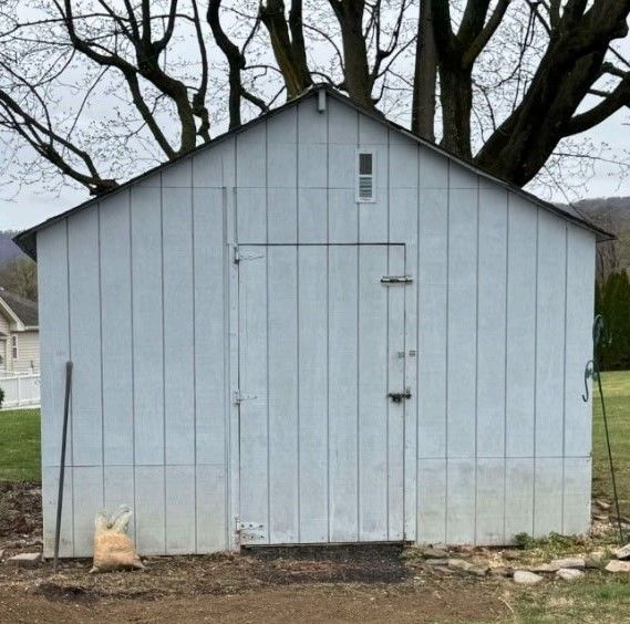 A white shed with a tree in the background
