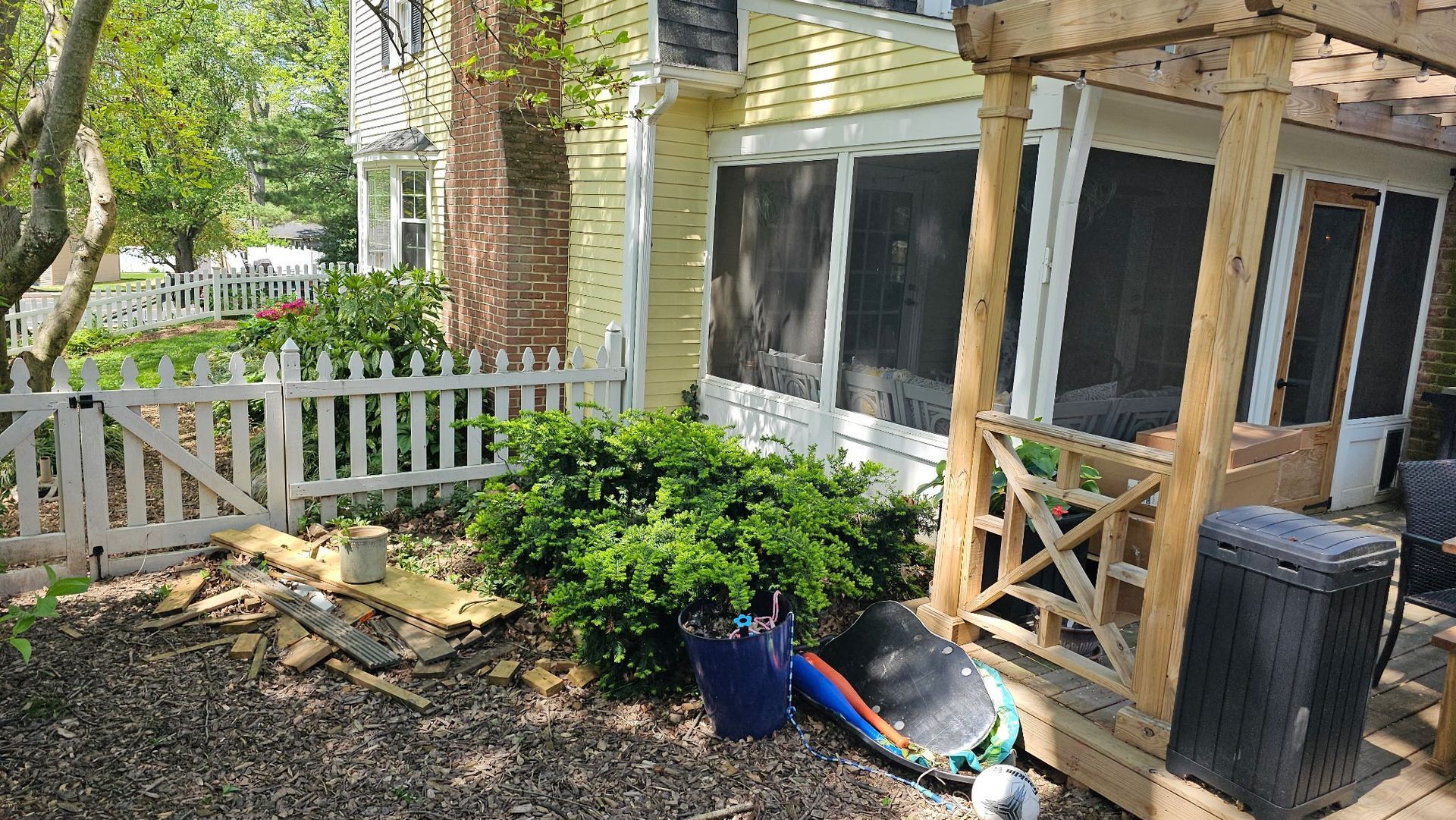A screened in porch with a white picket fence in front of a house