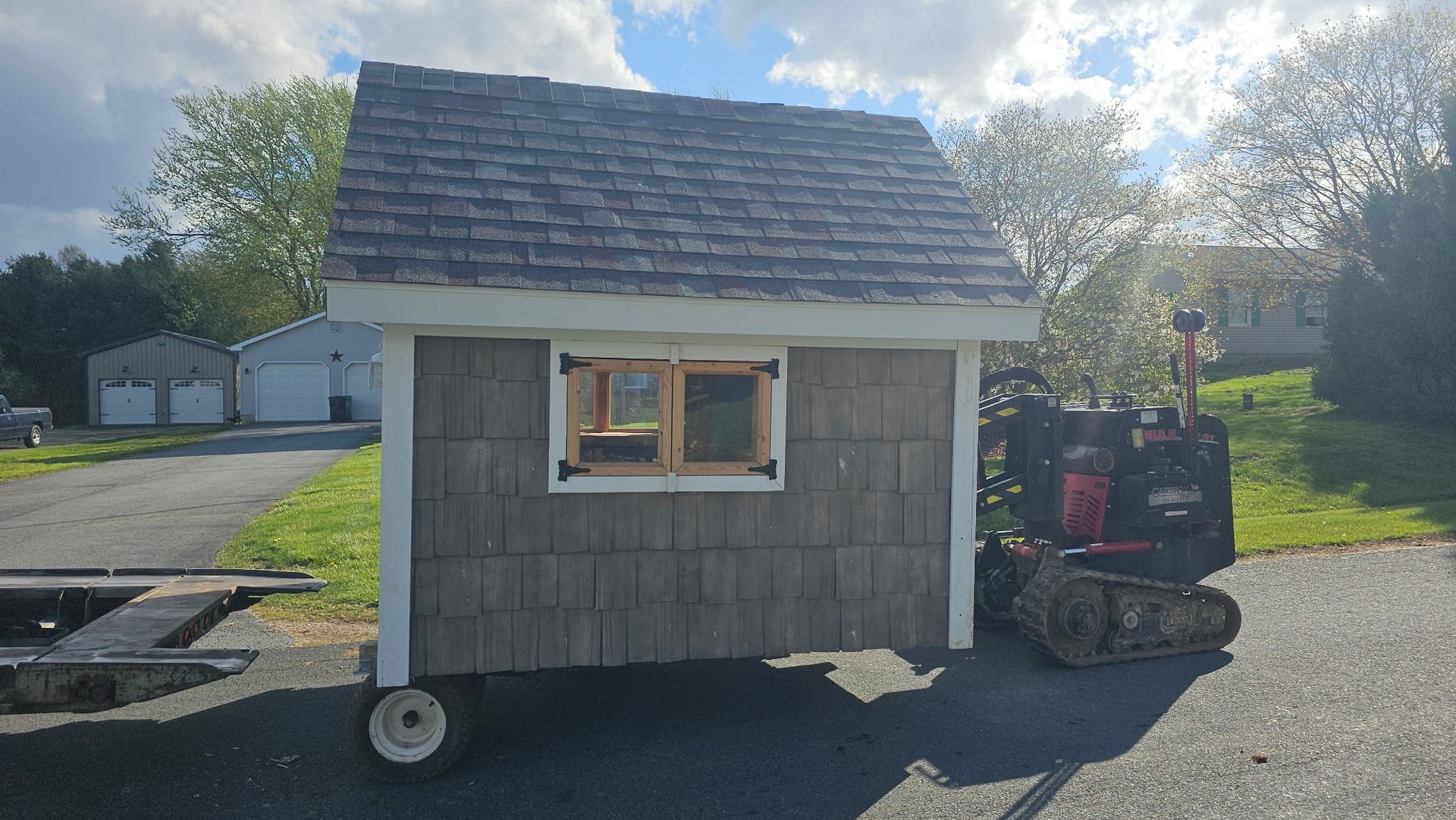 A small shed sitting on the side of a road next to a tractor