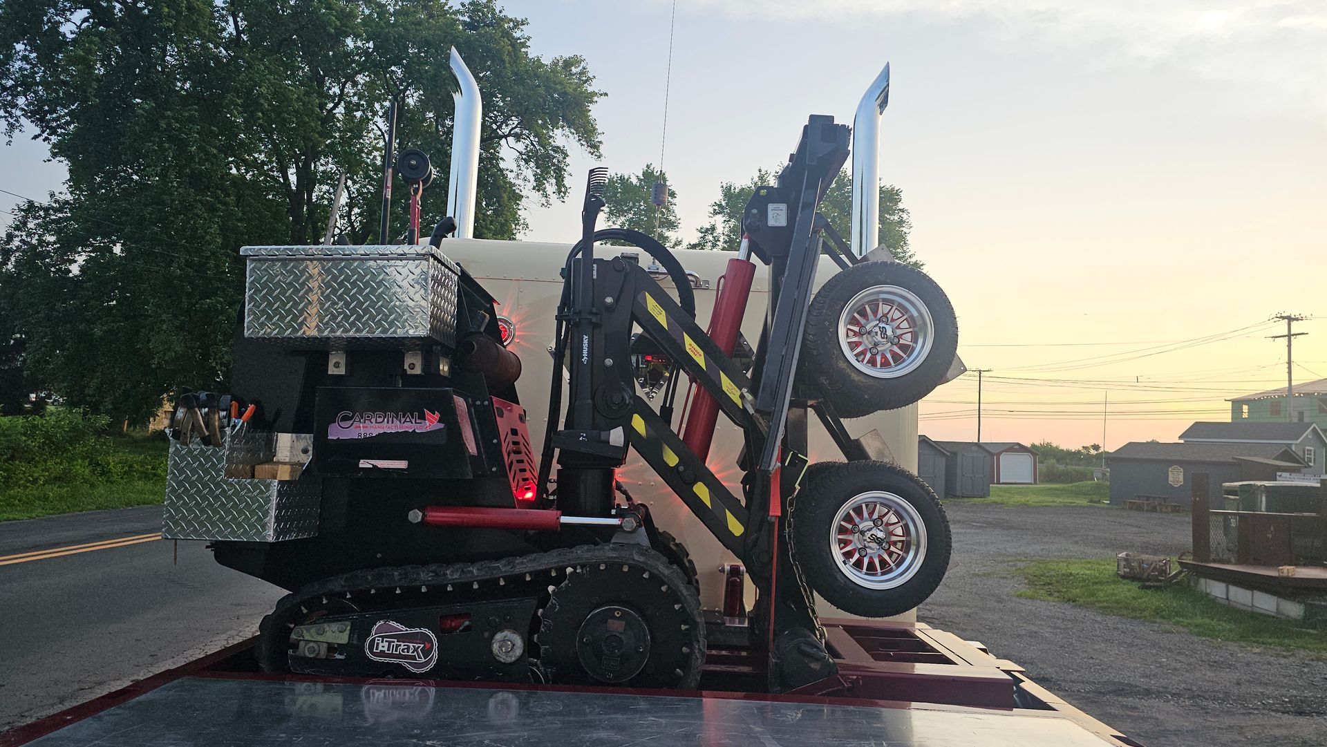 A tractor is sitting on top of a tow truck.