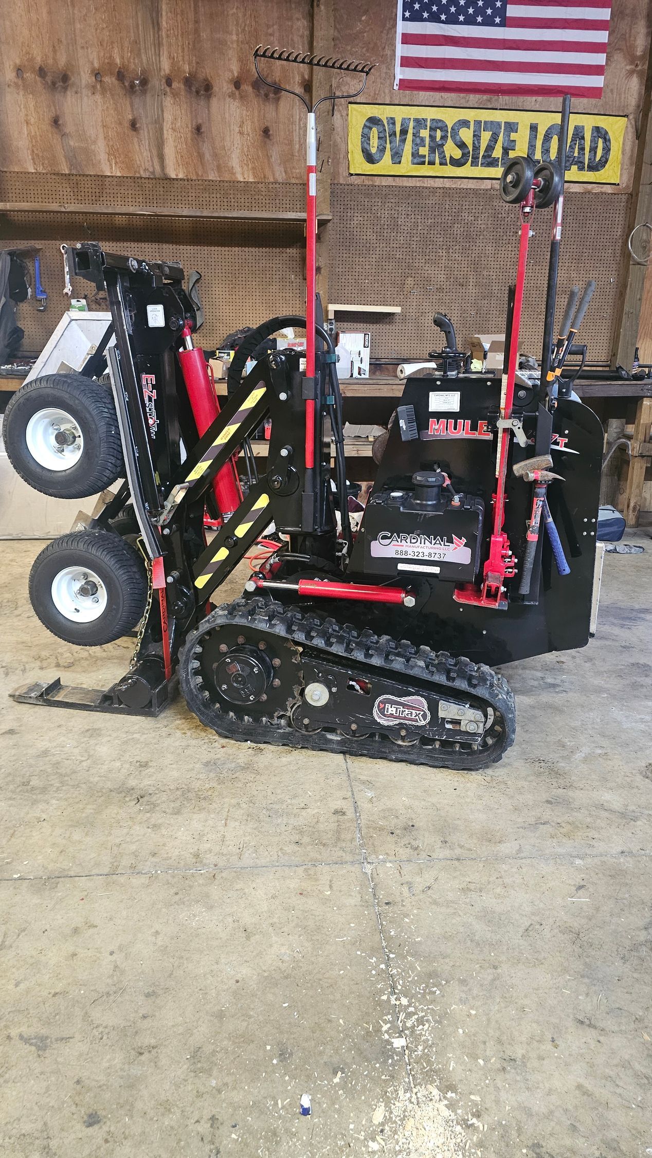 A small tractor is parked in a garage next to an american flag.