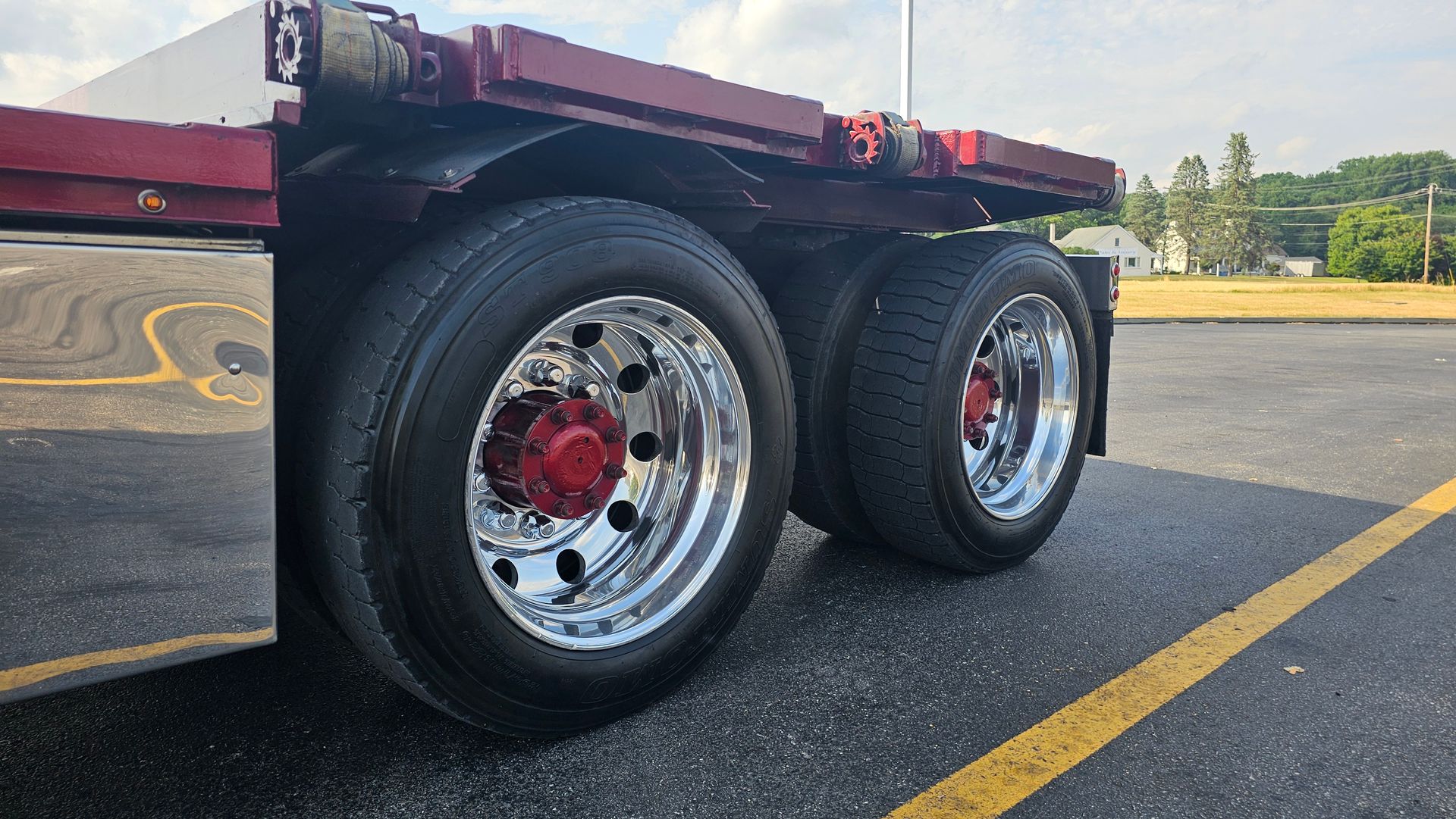 A semi truck with a flatbed trailer is parked in a parking lot.