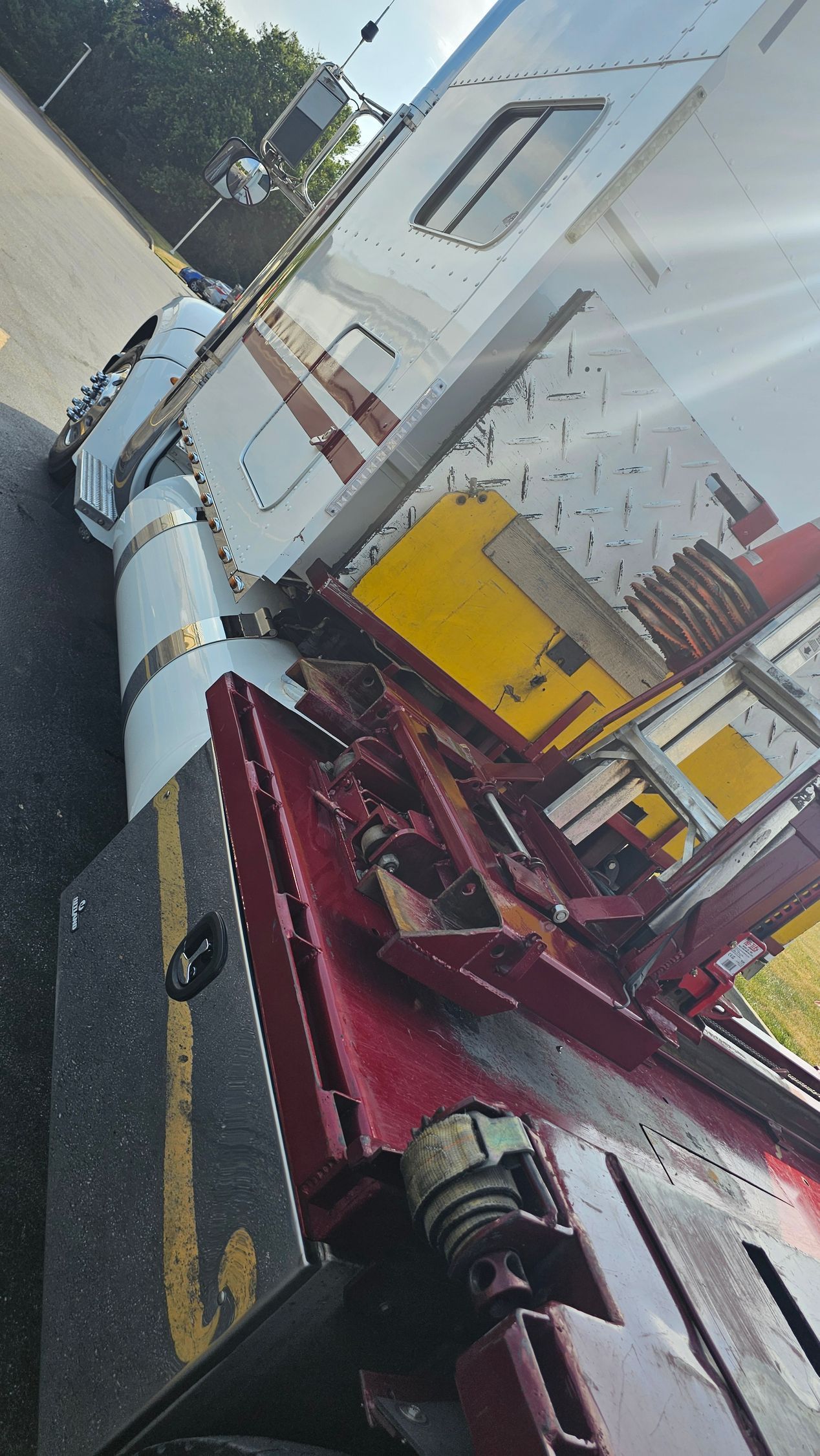 A red and white semi truck is parked on the side of the road.