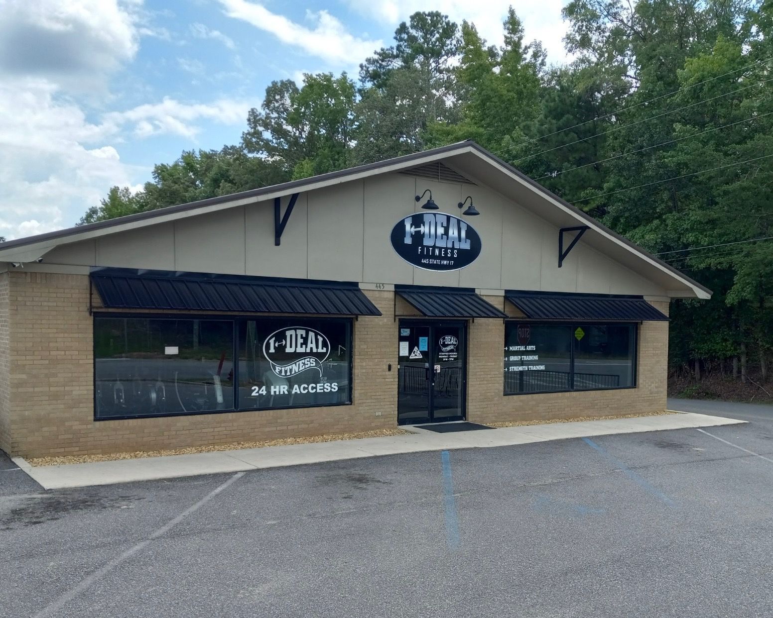 Exterior of a light brick building with black awnings and signage for 