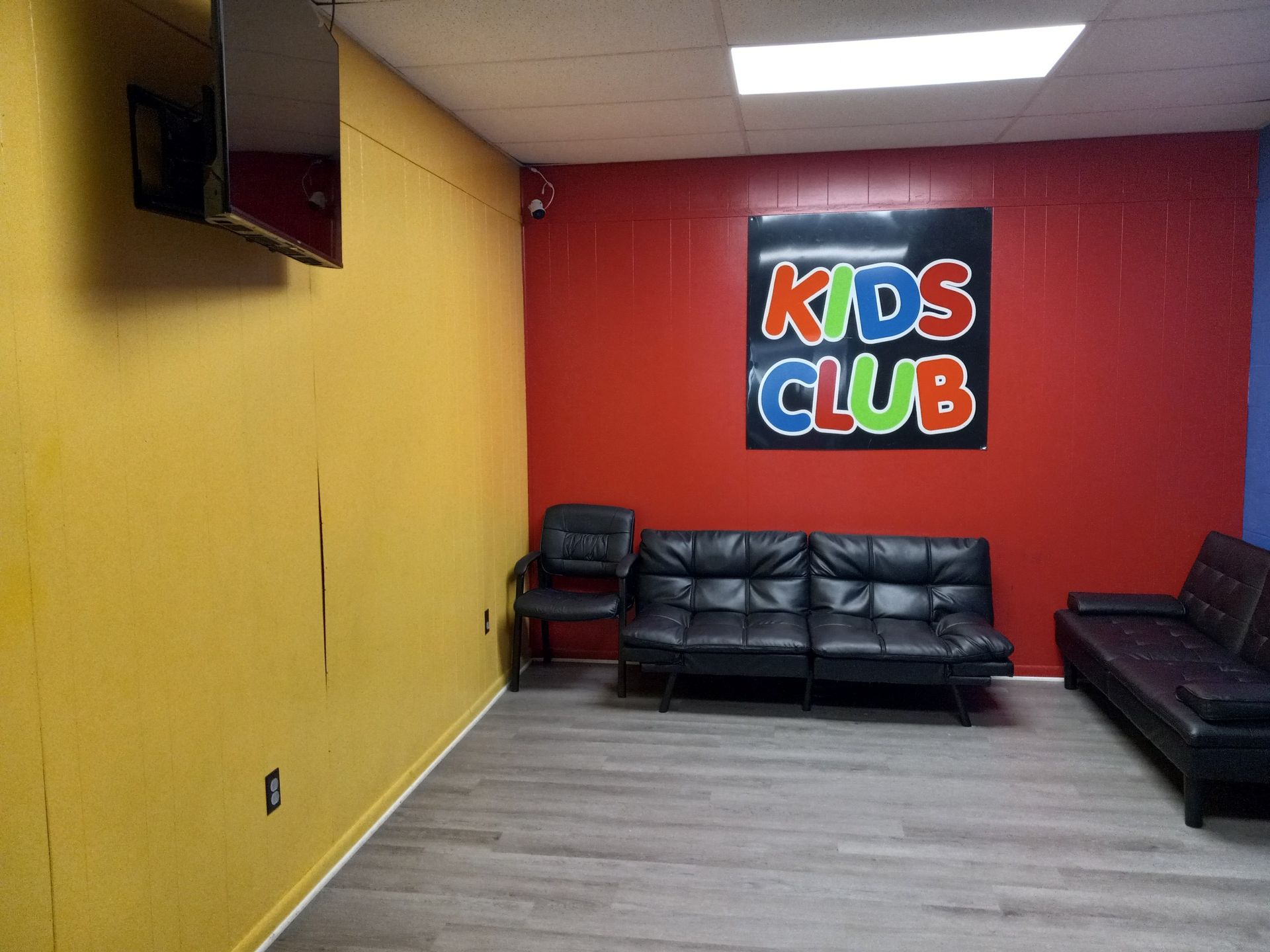 A Kids Club waiting area with a yellow wall, a red wall with a 